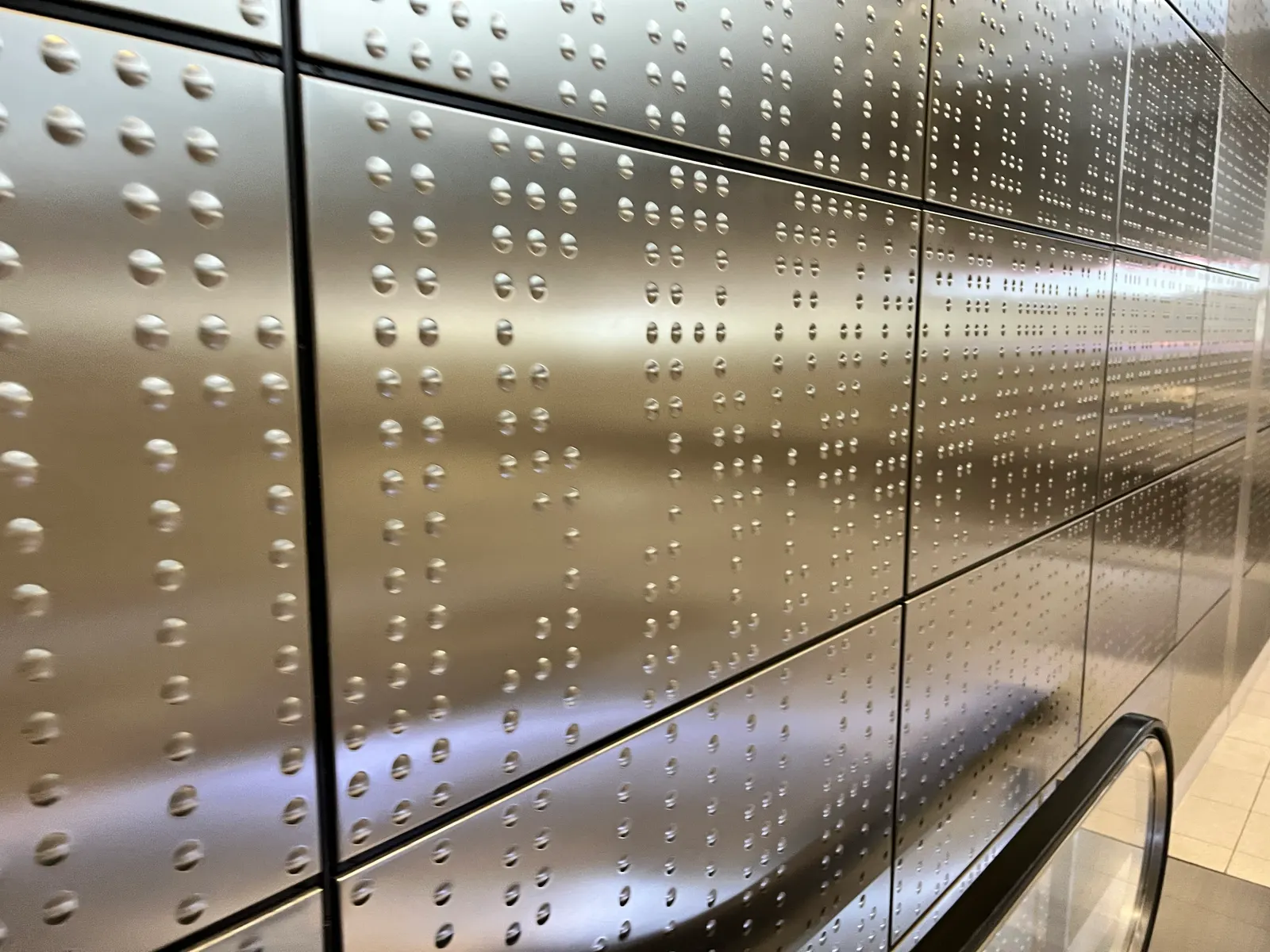 Silberne Wand mit geprägten Punkten in Blindenschrift.