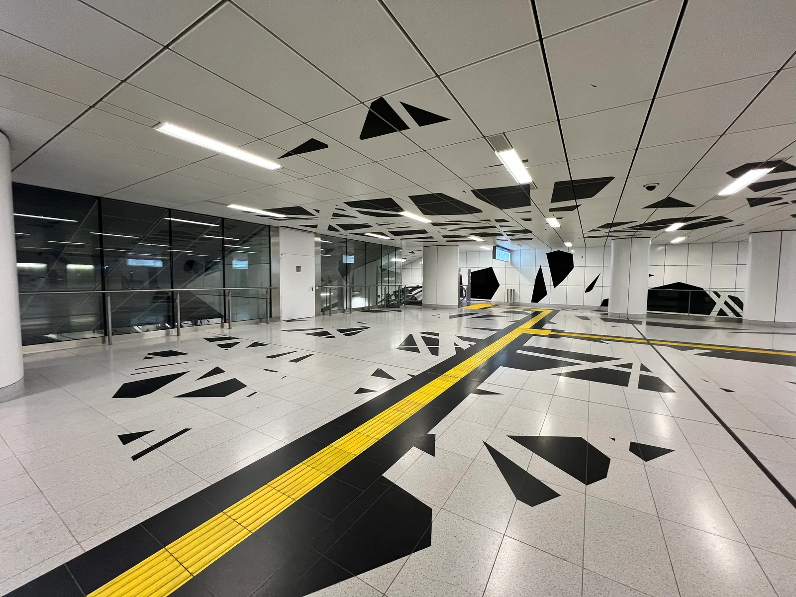 Bahnhofshalle mit gelber Leitlinie und schwarzen Splittern auf Boden und Decke.